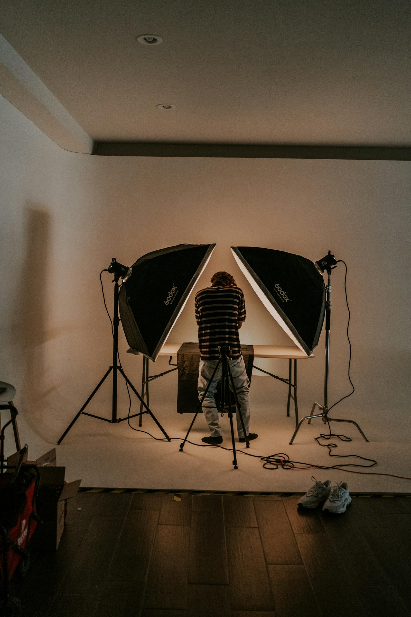 A single Profoto strobe firing through a 4×6 silk on a Brooklyn rooftop at golden hour, two stylists holding the frame against the wind.